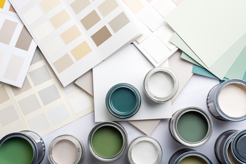 Tiny sample paint cans during house renovation, process of choosing paint for the walls, different green and beige colors, color charts on background