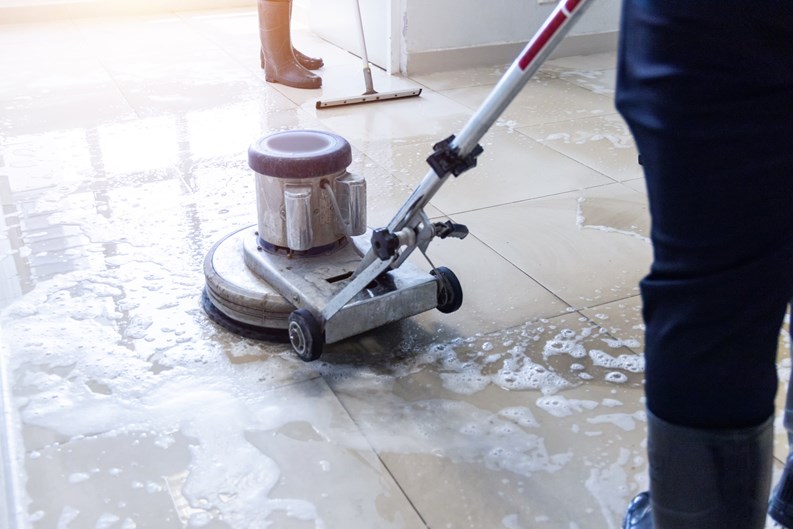 Janitor use floor scrubber machine on the floor hallway office building or walkway after school and classroom work job with sun light background. Wet floor or cleaning service house maid concept.